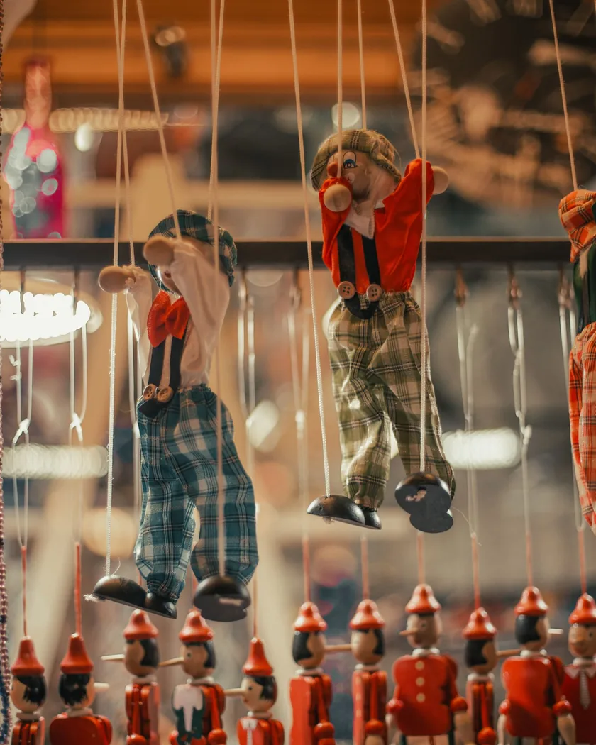 Marionetas de madera colgadas de sus hilos, con los pies sin apoyo y los brazos ligeramente levantados